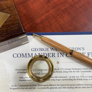 Wooden pen, magnifying glass, and historical document on a wooden surface